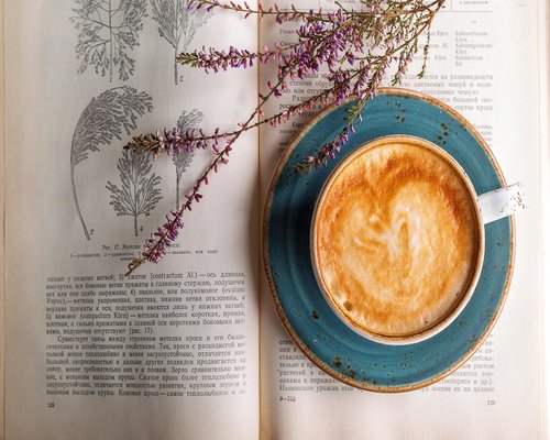 Person drinking coffee and reading a book in an outdoor cafe in Spain